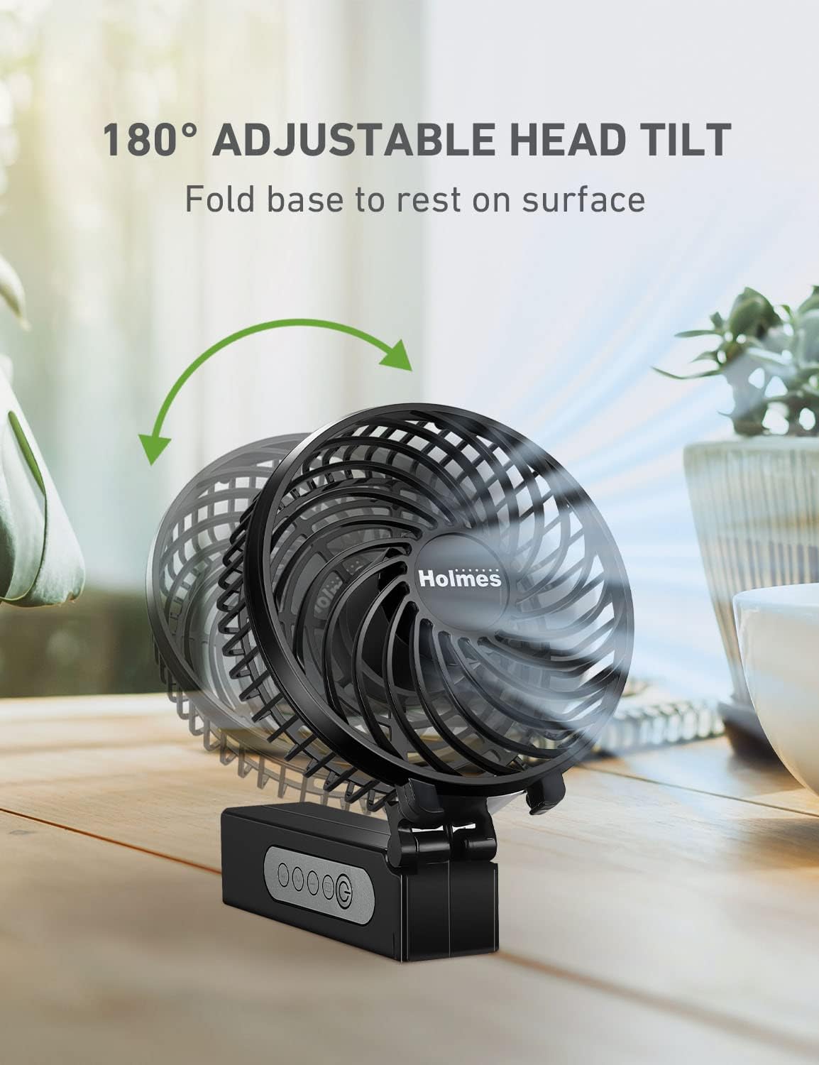 HOLMES 4-Inch Portable Rechargeable Personal Fan showing its 180-degree adjustable head tilt feature on a wooden table
