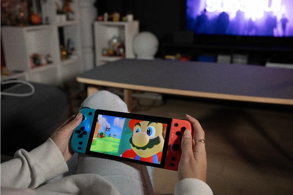 A person holding the blue and red Konix Joypads wirelessly, with a TV screen in the background showing a game.