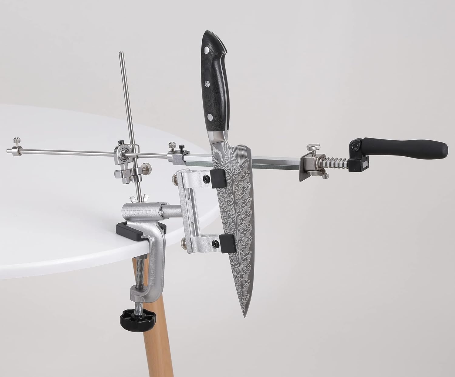 The RUIXIN PRO RX-009 Knife Sharpener clamped to a white table, holding a knife securely in place, ready for sharpening.