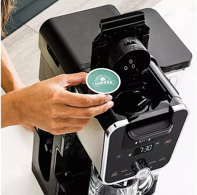 A hand inserting a coffee pod into the Ninja DualBrew PRO XL's pod adapter.