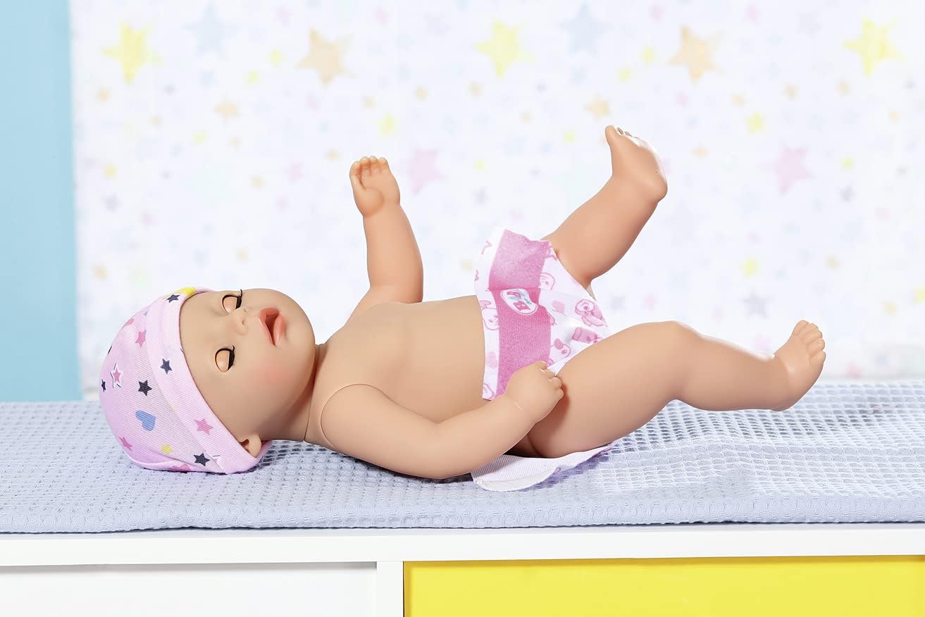 A hand holding a yellow bottle to the Baby Born doll's mouth as she lies on her back, drinking.