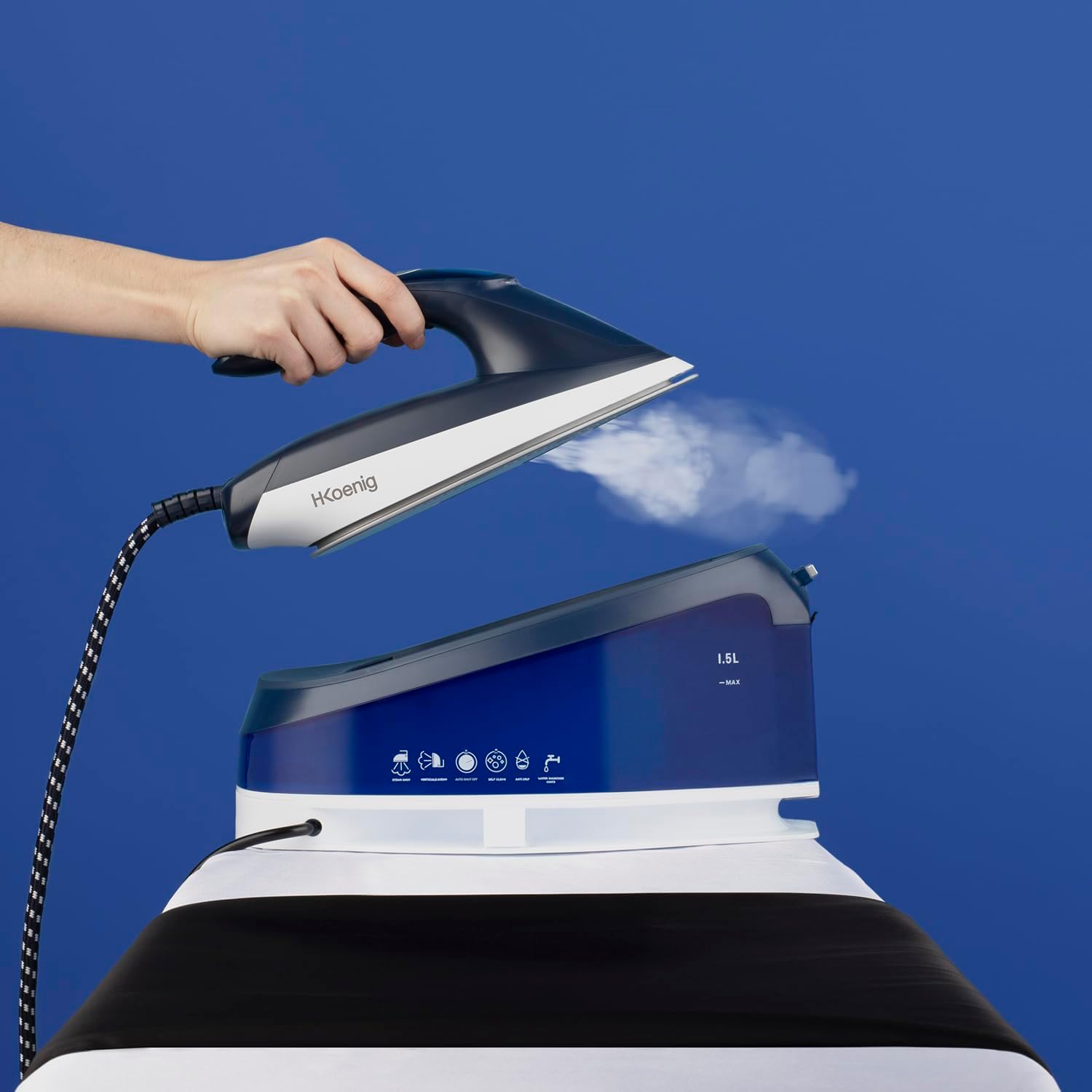 Hand holding H.Koenig V7 iron vertically, steaming a garment