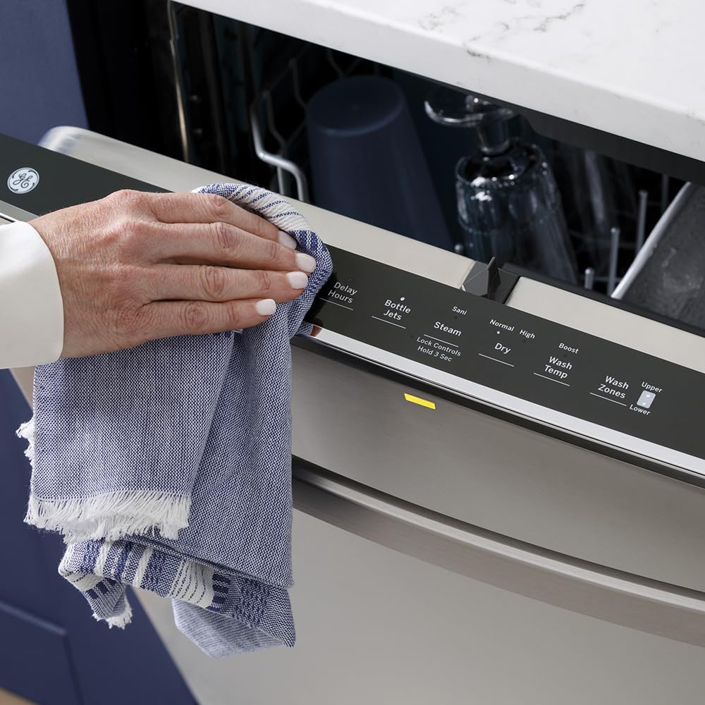 A hand wiping the stainless steel exterior of the GE dishwasher with a cloth.