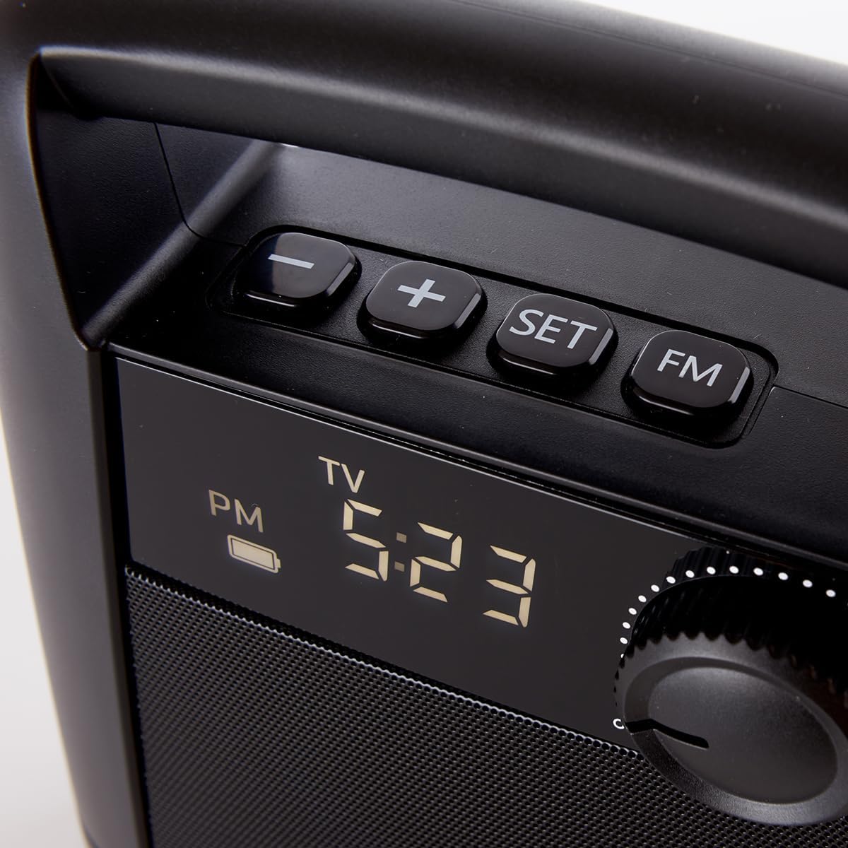 Close-up of the top panel of the wireless TV speaker, showing the volume knob, plus/minus buttons, SET button, FM button, and the digital display showing 'TV' and '5:23 PM'.