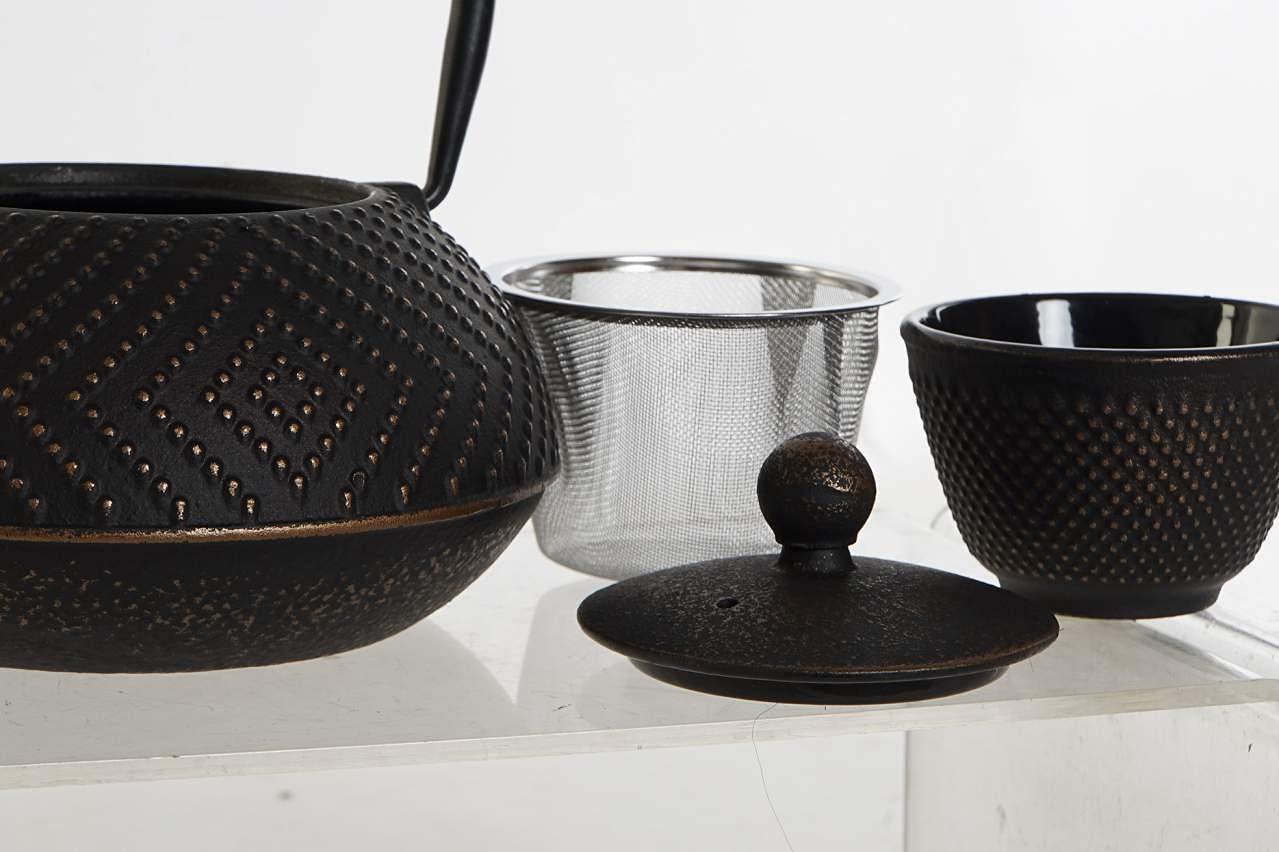 Tetera de hierro fundido negro y dorado con cesta inoxidable, acompañada de sus 2 tazas de té.