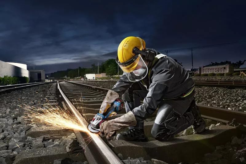 Worker using BOSCH angle grinder to cut metal on a railway track