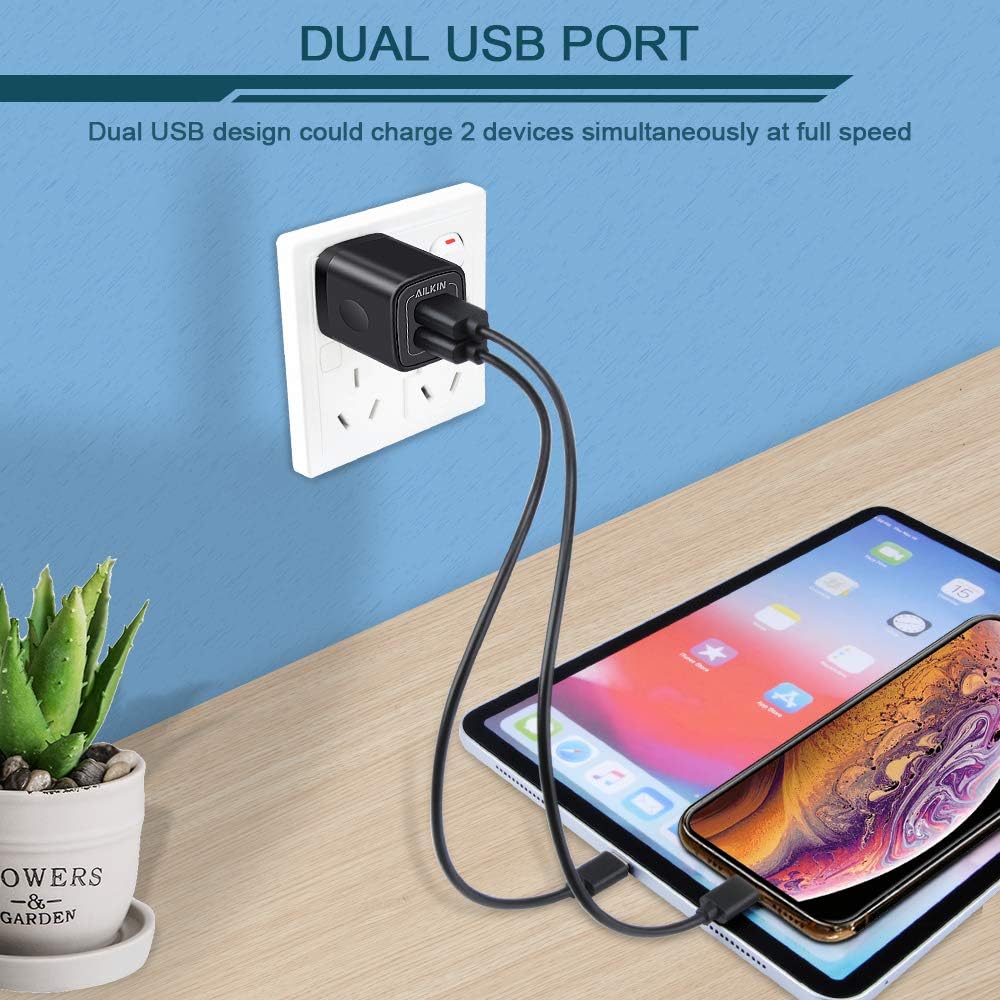 AILKIN Dual USB Port Charger plugged into a wall outlet, charging a tablet and a smartphone.