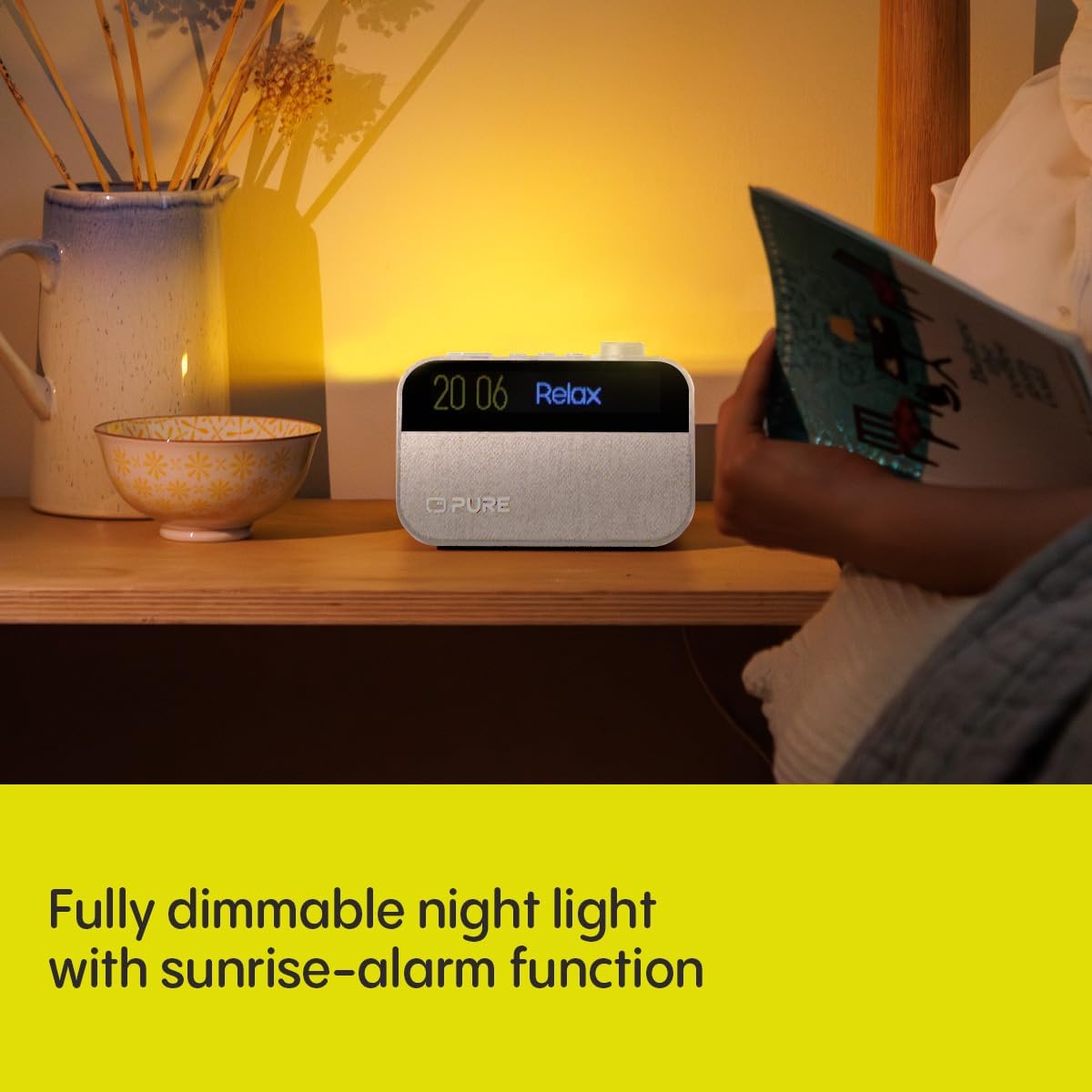 Pure Moment alarm clock on a bedside table, emitting a warm glow as a night light.