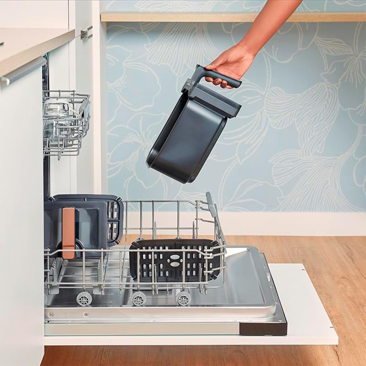 One of the Amsta AMDF9ADVB air fryer baskets being placed into a dishwasher, demonstrating its dishwasher-safe feature.