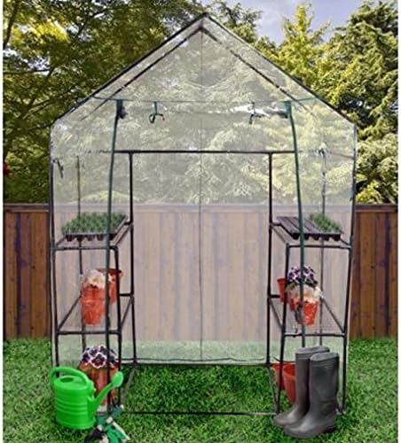Greenhouse in a garden setting with plants and gardening tools