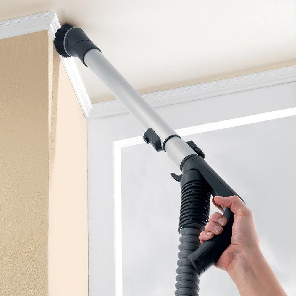 Person using the Miele S7210 Twist extension wand with a brush attachment to clean a high corner