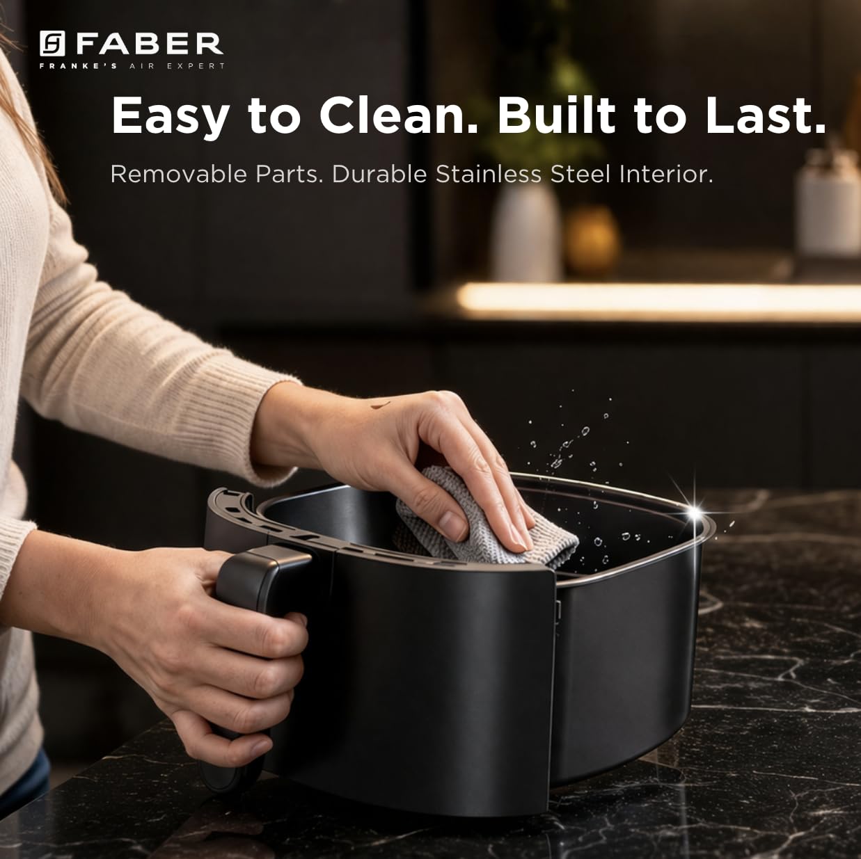 Person cleaning the Faber FAF CrispX 4.0 Digital Air Fryer basket