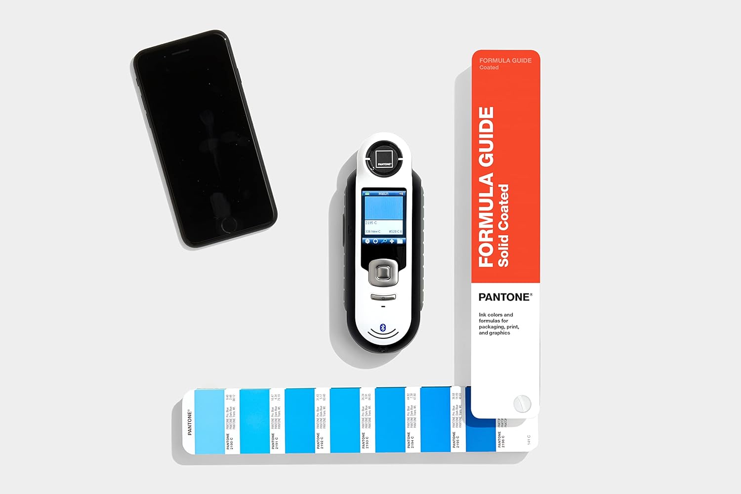 Pantone CAPSURE device next to a Pantone Formula Guide, showing color matching capabilities.
