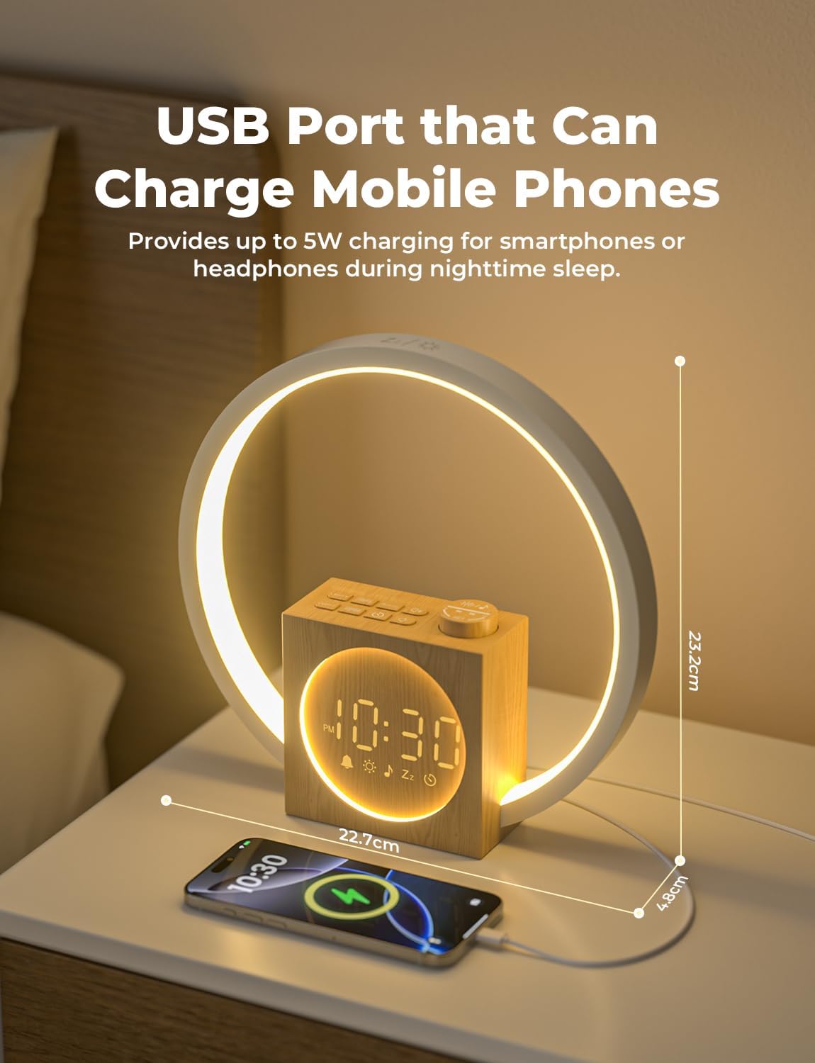 The alarm clock on a bedside table with a smartphone connected to its USB port for charging.