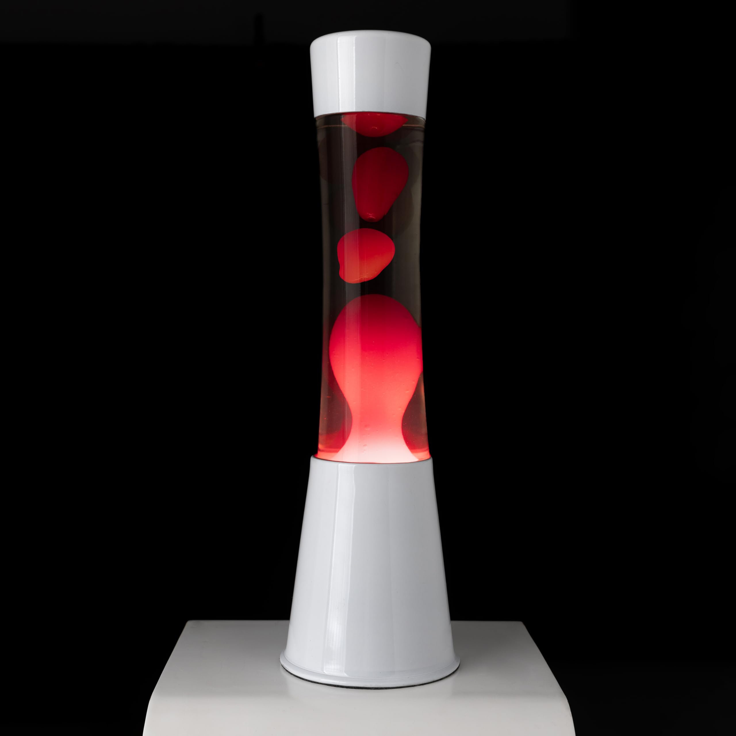 Fisura – Lámpara de lava roja y blanca. Base blanca, líquido transparente y lava roja. Lámpara con efecto relajante. Incluye bombilla de repuesto. 11 cm x 11cm x 41,5 cm.