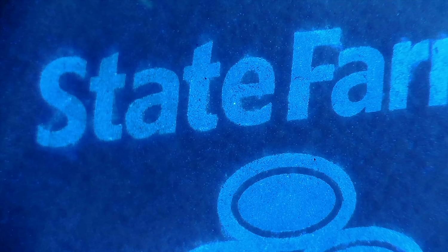 Dibesarkan view of a 'StateFarm' logo under UV light, showing fluorescent properties.
