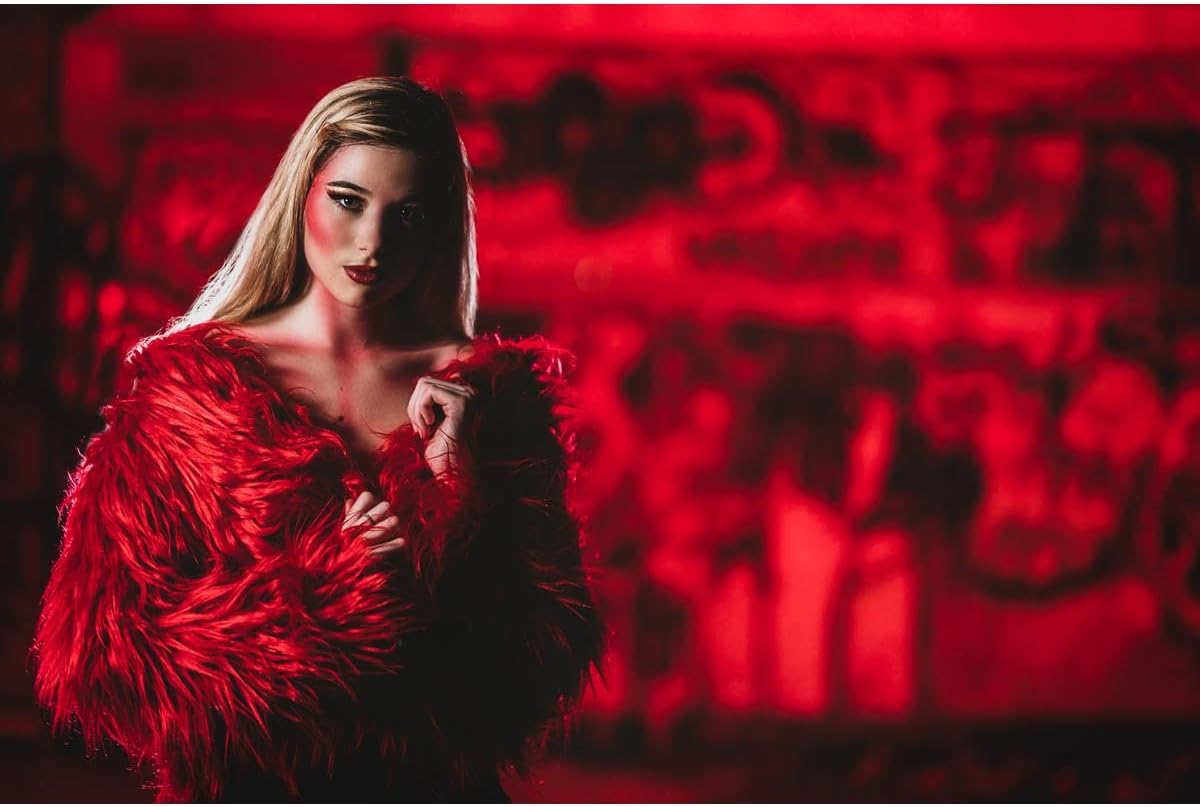 A woman in a red fur coat illuminated by intense red light from the Rotolight Titan X1
