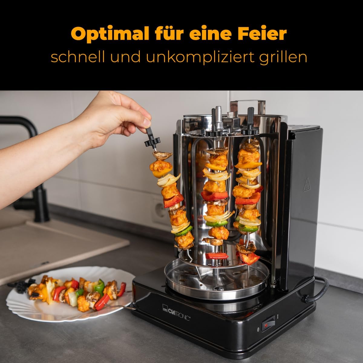 All removable components of the Clatronic DVG 3686 Multigrill laid out, including the large spit, small skewers, fat tray, and tongs.