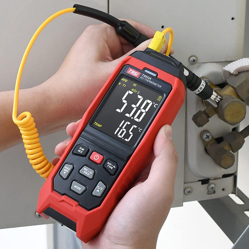 TASI TA612C thermometer in use, with a K-type thermocouple probe connected and measuring temperature on a pipe.