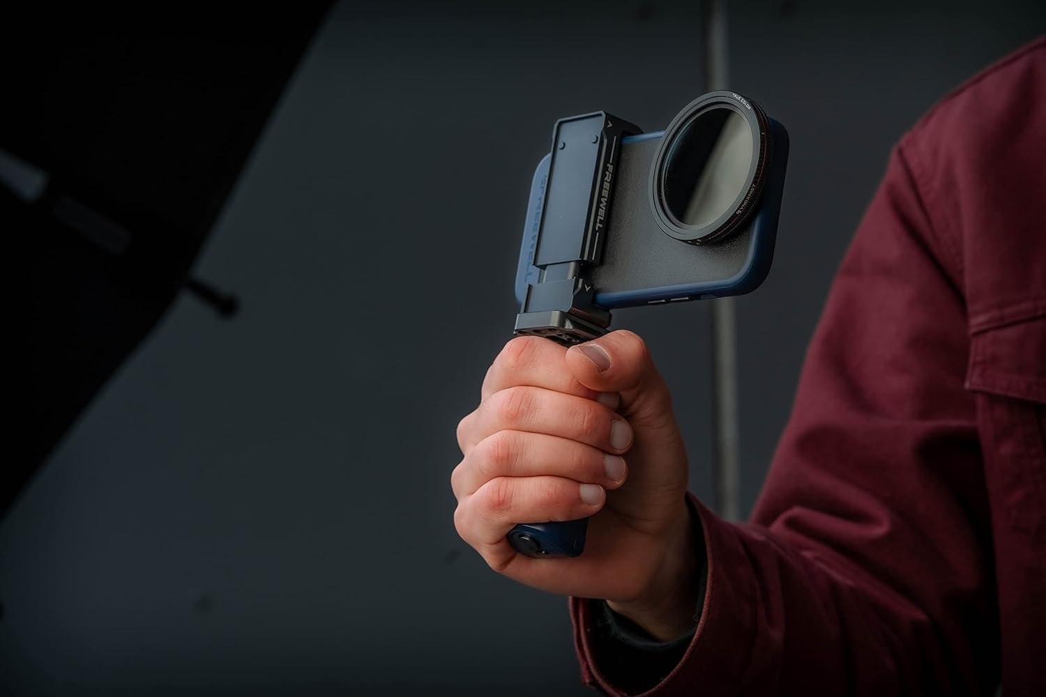 A hand holding the Freewell grip with a smartphone attached, demonstrating comfortable handling.