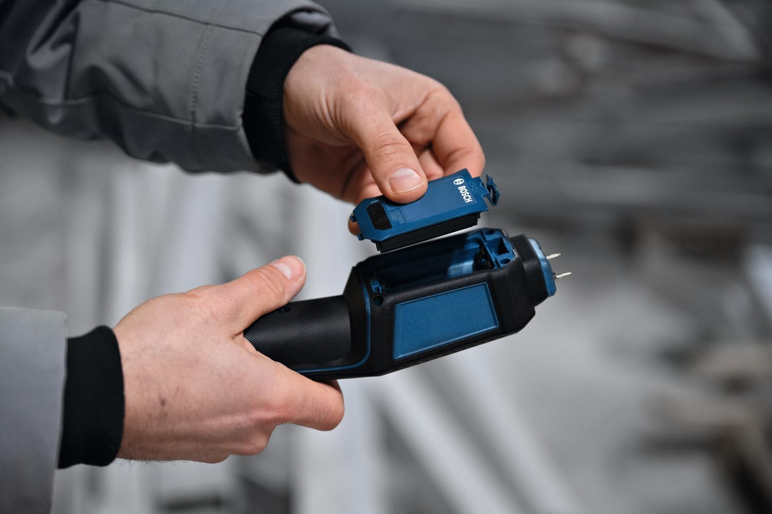 Hands installing batteries into the Bosch Professional GMP 2-15 Moisture Meter