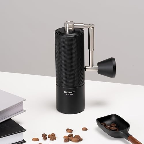 The TIMEMORE C3S Pro grinder standing on a desk beside coffee beans and a scoop, showing the knurled grip texture on the body