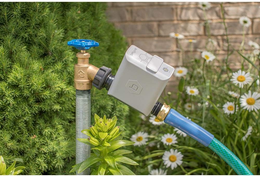 Orbit B-Hyve Smart Hose Faucet Irrigation Controller attached to an outdoor faucet with a garden hose connected