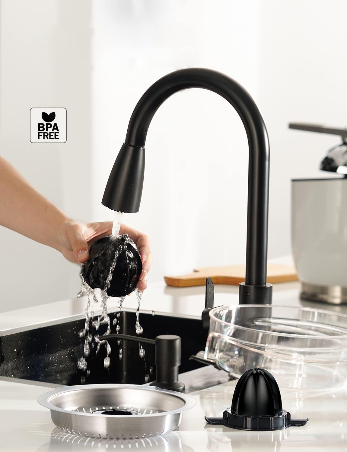 Hand washing a juicer component under a kitchen faucet, with other parts laid out for cleaning.