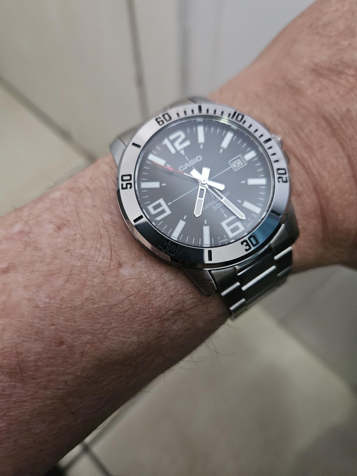Relógio Casio sendo usado no pulso masculino mostrando o ajuste da pulseira de metal