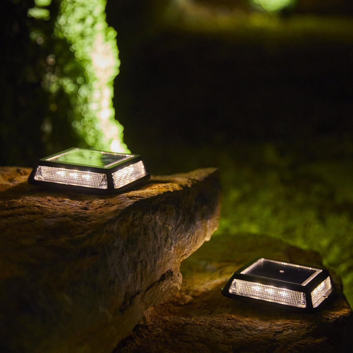 Two Lumisky QUADRY solar lights glowing with warm white light on a rocky garden surface at night.
