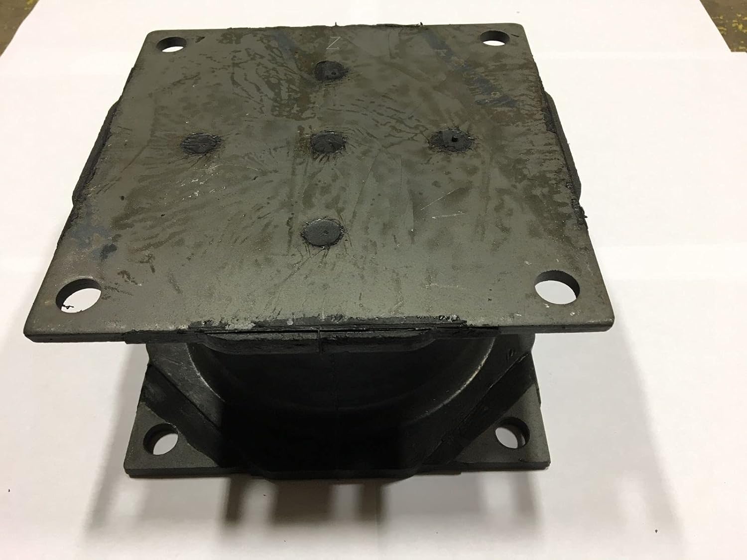 Side view of the HDI rubber isolator shock mount, showing the rubber component between two metal plates with bolt holes.