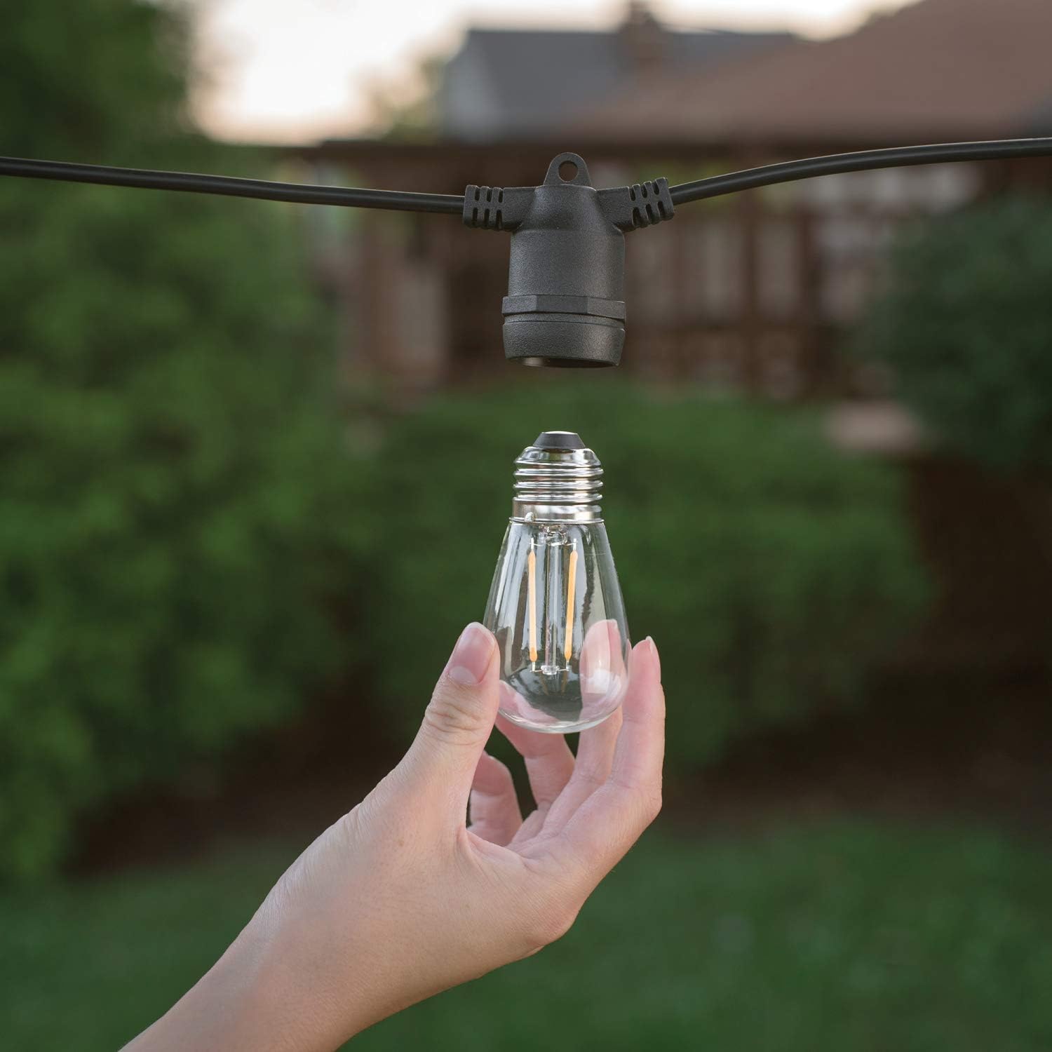 Hand holding an S14 LED bulb next to an empty socket
