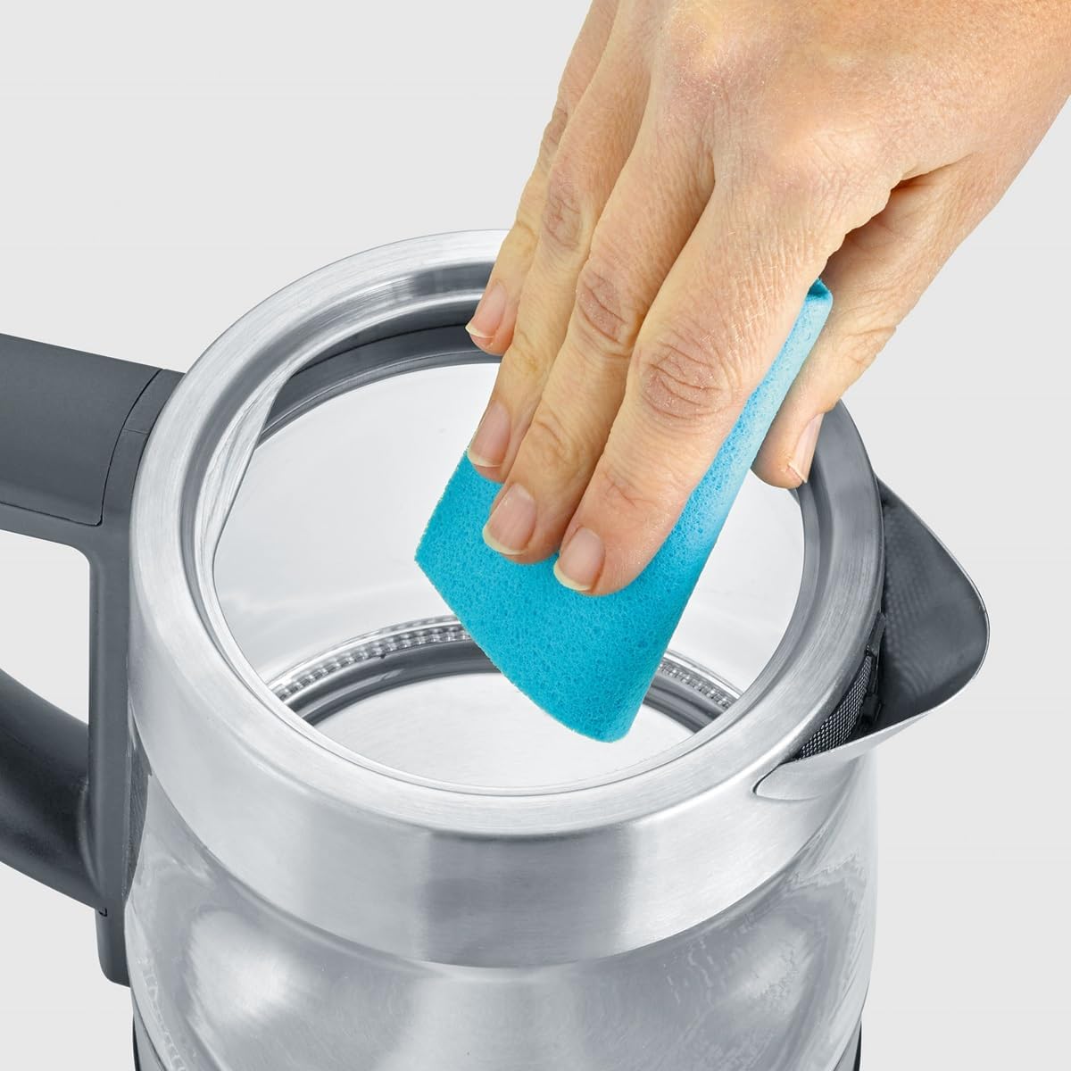 A hand cleaning the inside of the SEVERIN kettle with a blue sponge.