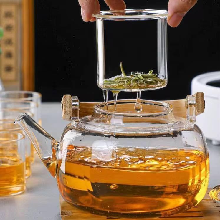 Hand removing the glass infuser filled with steeped tea leaves from the teapot