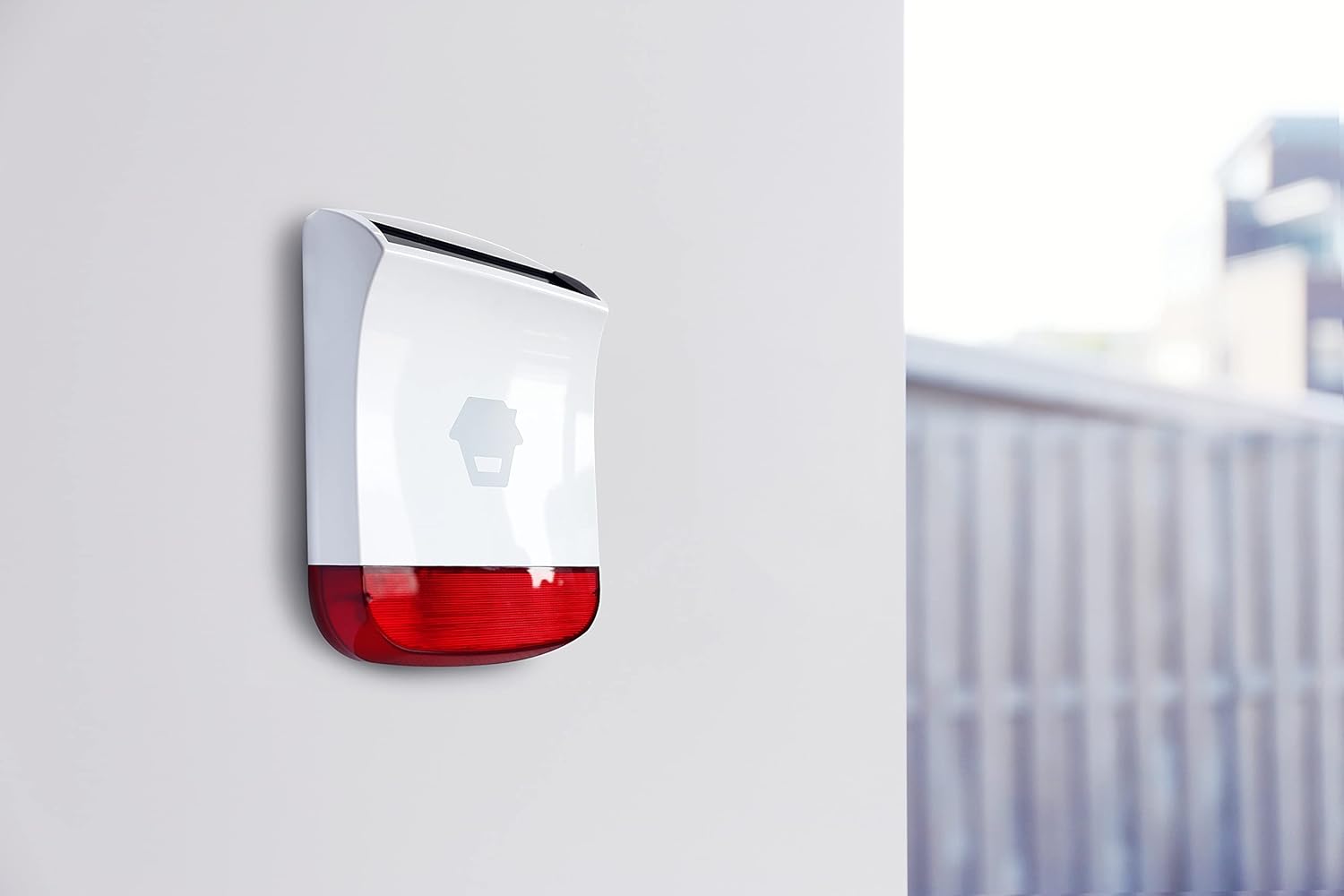 બાજુ view of the Chuango SPS-260 Solar Wireless Siren mounted on a white wall, showing its sleek profile અને સૌર પેનલ.