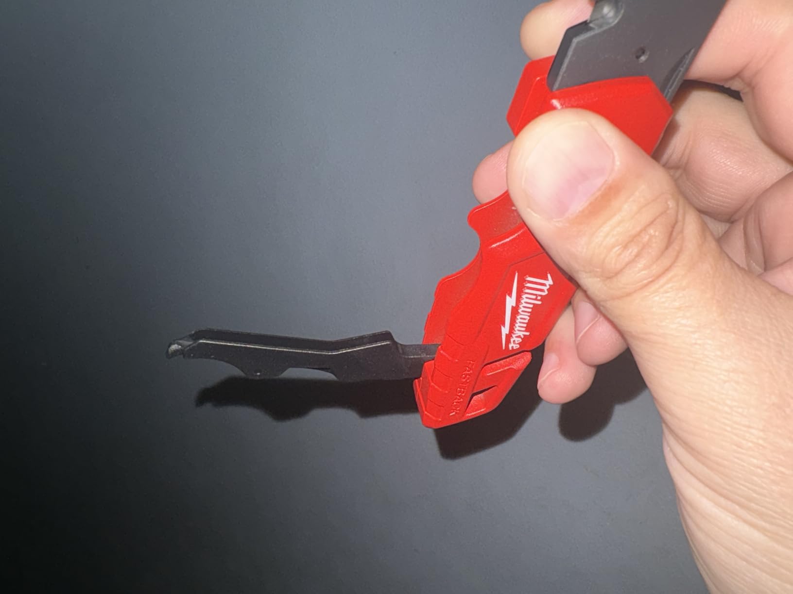 Milwaukee Fastback utility knives on a construction site background