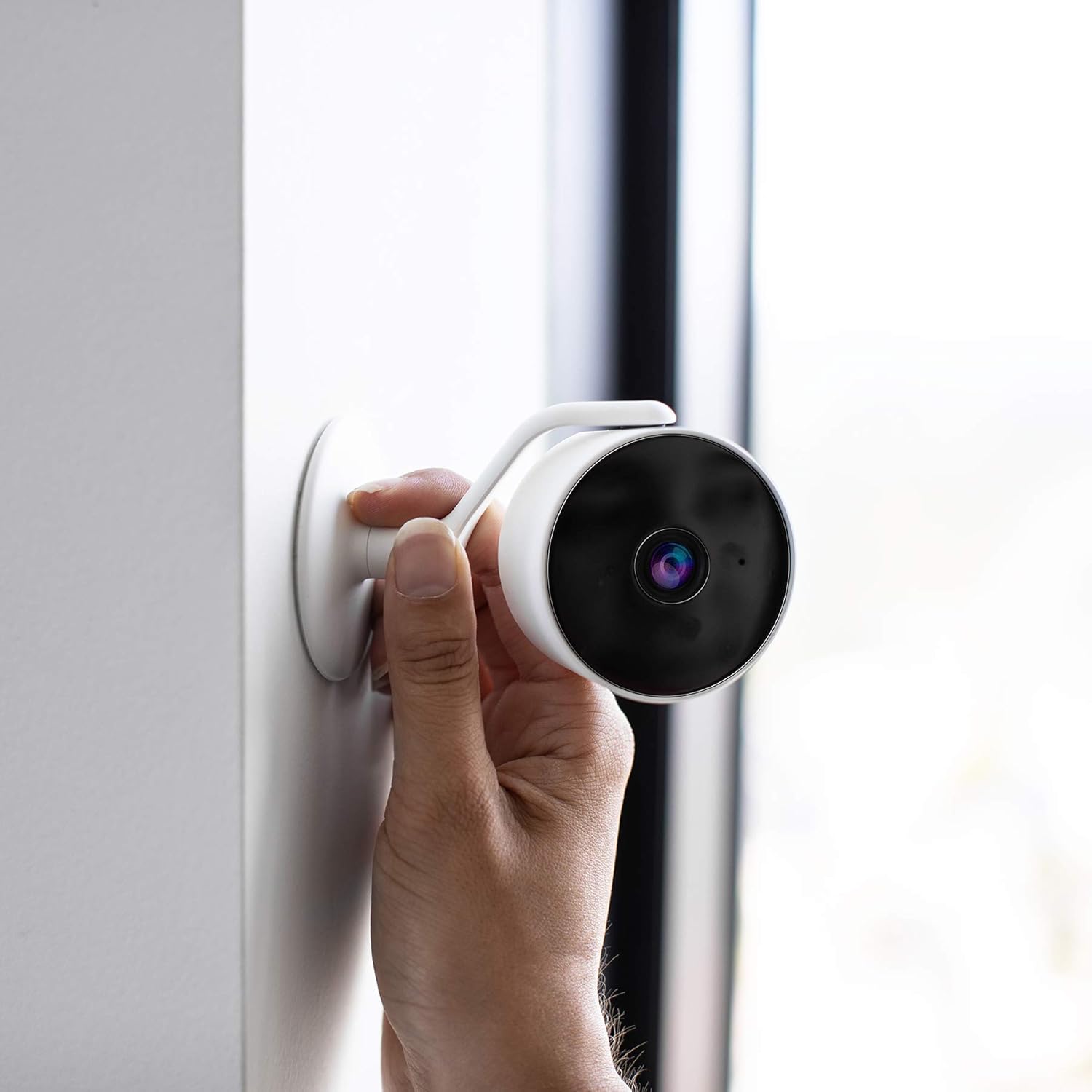 Hand holding the Hombli Smart Indoor Camera, demonstrating wall mounting.
