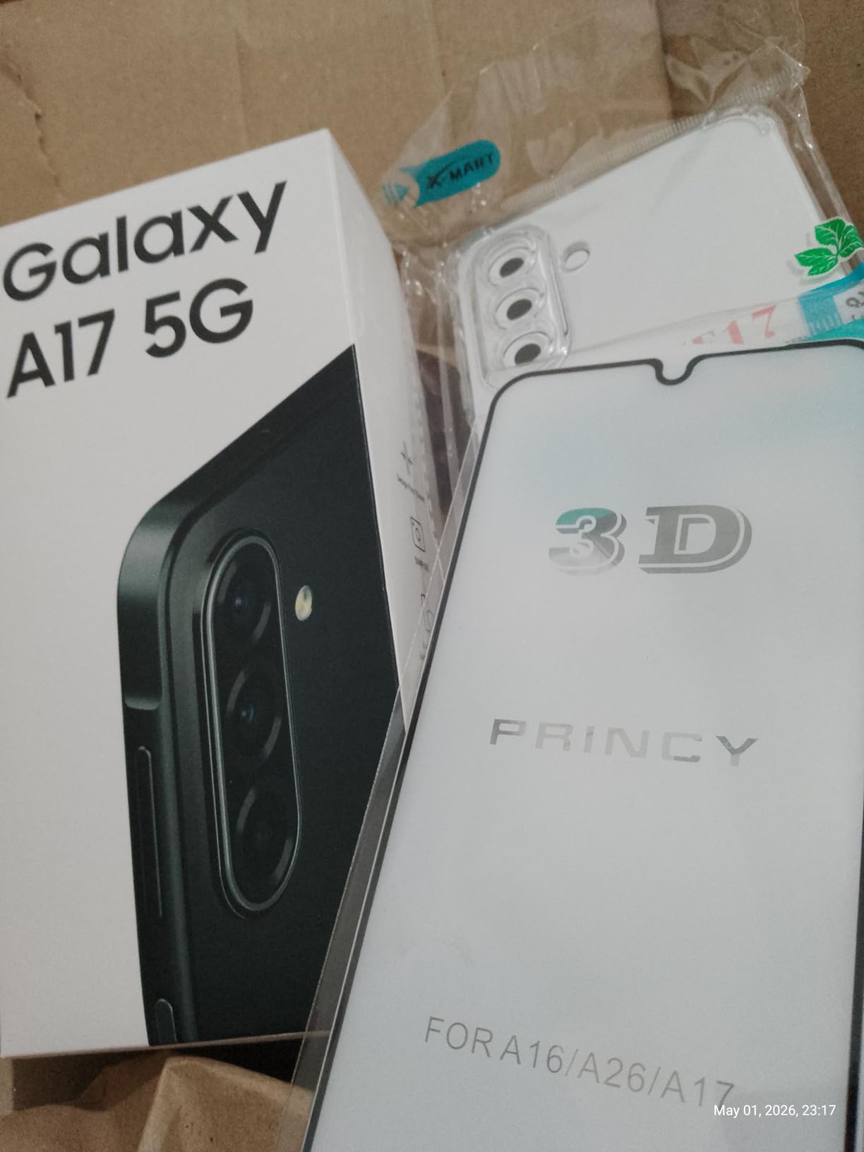 Caixa do celular Galaxy A17 5G ao lado de uma película de proteção de tela 3D e uma capinha transparente