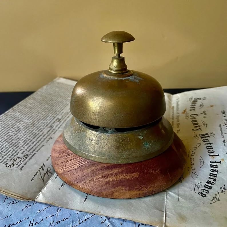 Campana de latón vintage para recepción de hotel o escritorio sobre base de madera