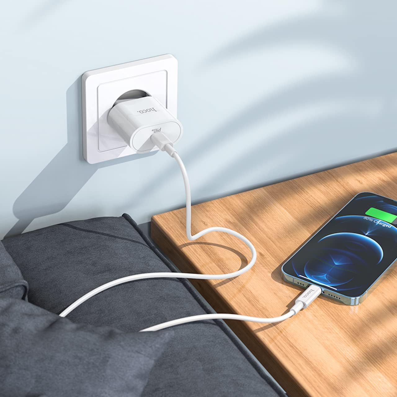 HOCO C94A Metro 20W Fast Charger plugged into a wall outlet, charging an iPhone