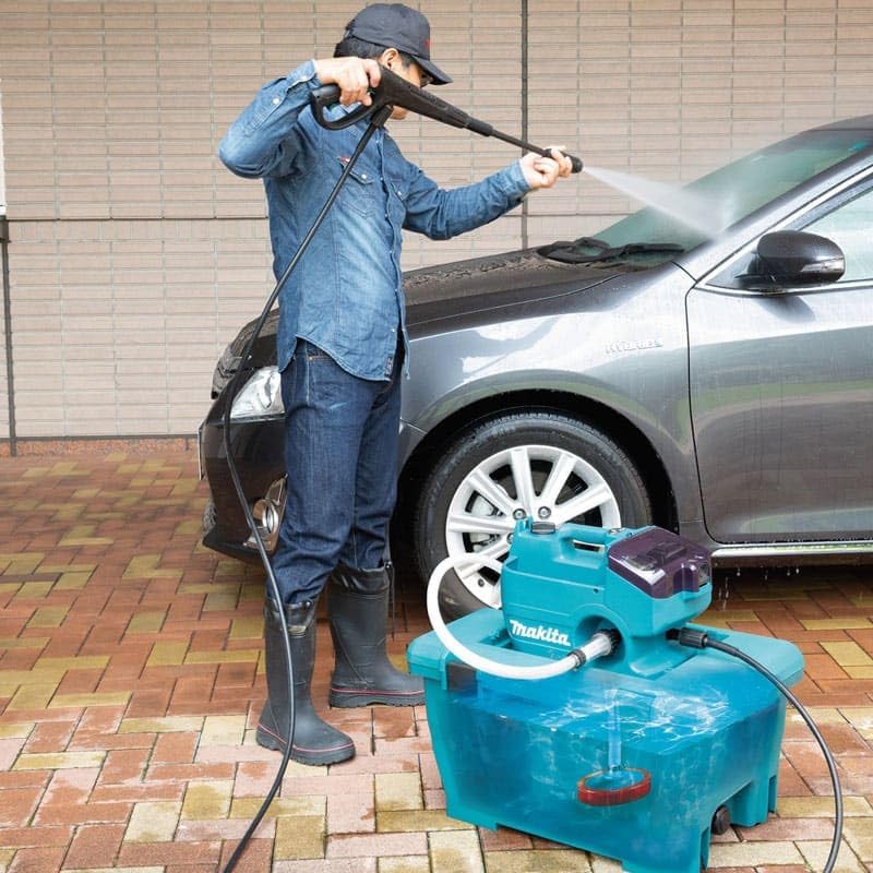 Man using Makita DHW080ZK pressure washer to clean a car.
