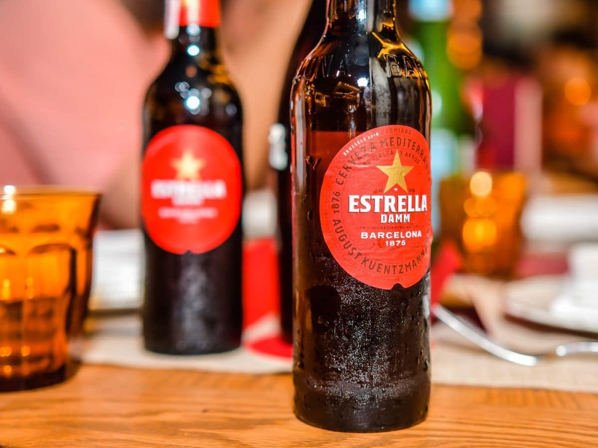 Estrella Damm 12 x 0,33l - das beliebteste Bier der Katalanen mit 5,4% Vol. - Spanisches Pils- Inklusive Haus der Biere Berlin Bierdeckel