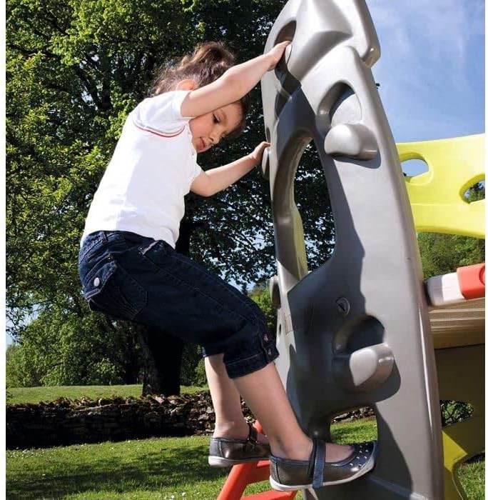 Child climbing a grey climbing wall section of the Smoby tower