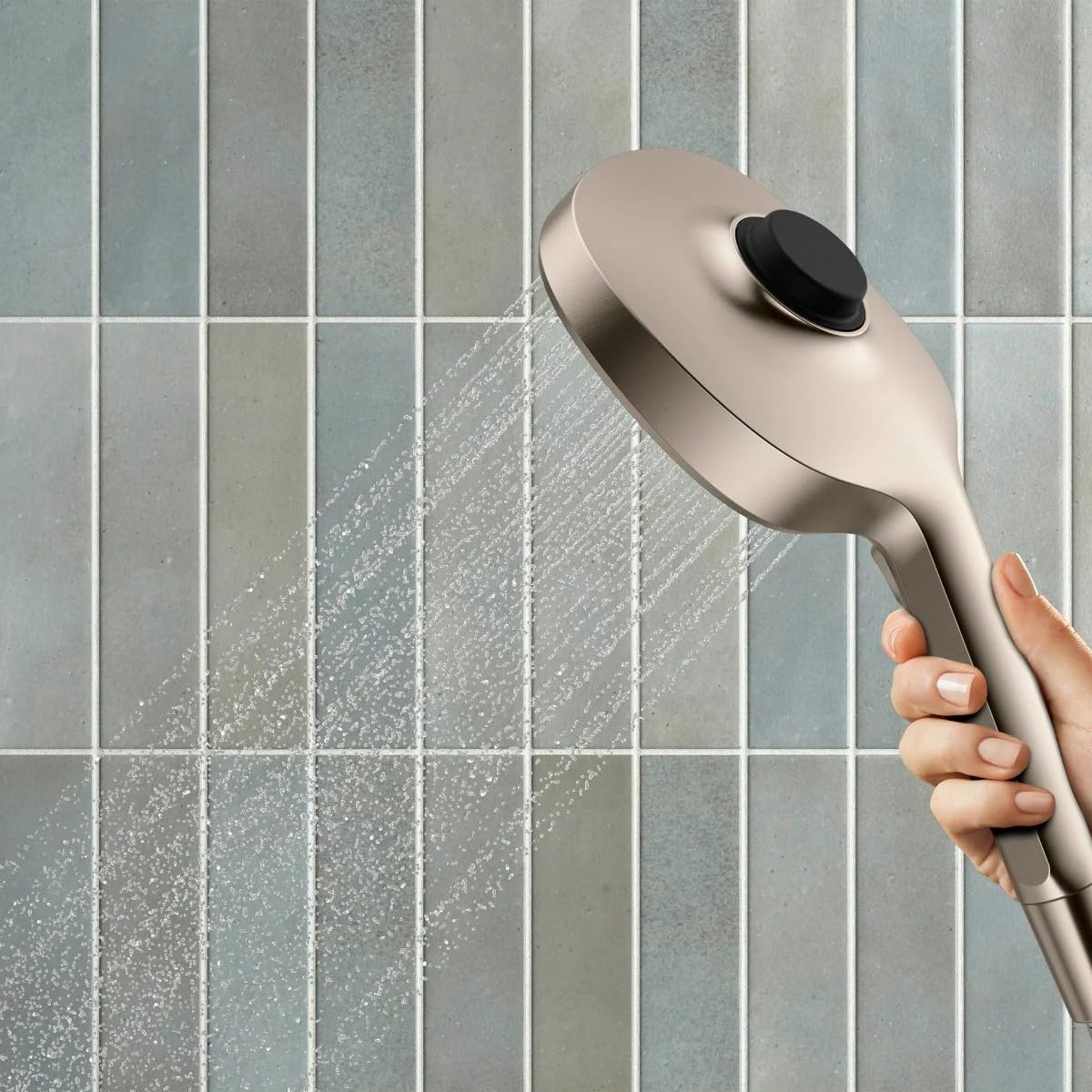 A hand holding the Kohler Tellin Handshower, demonstrating the water spray.