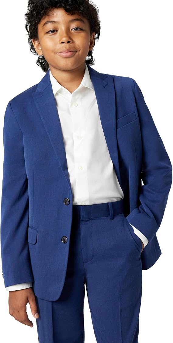 A boy wearing a medium blue two-piece suit consisting of a single-breasted blazer with two dark buttons and flap pockets, paired with matching straight-leg trousers and a white dress shirt underneath.