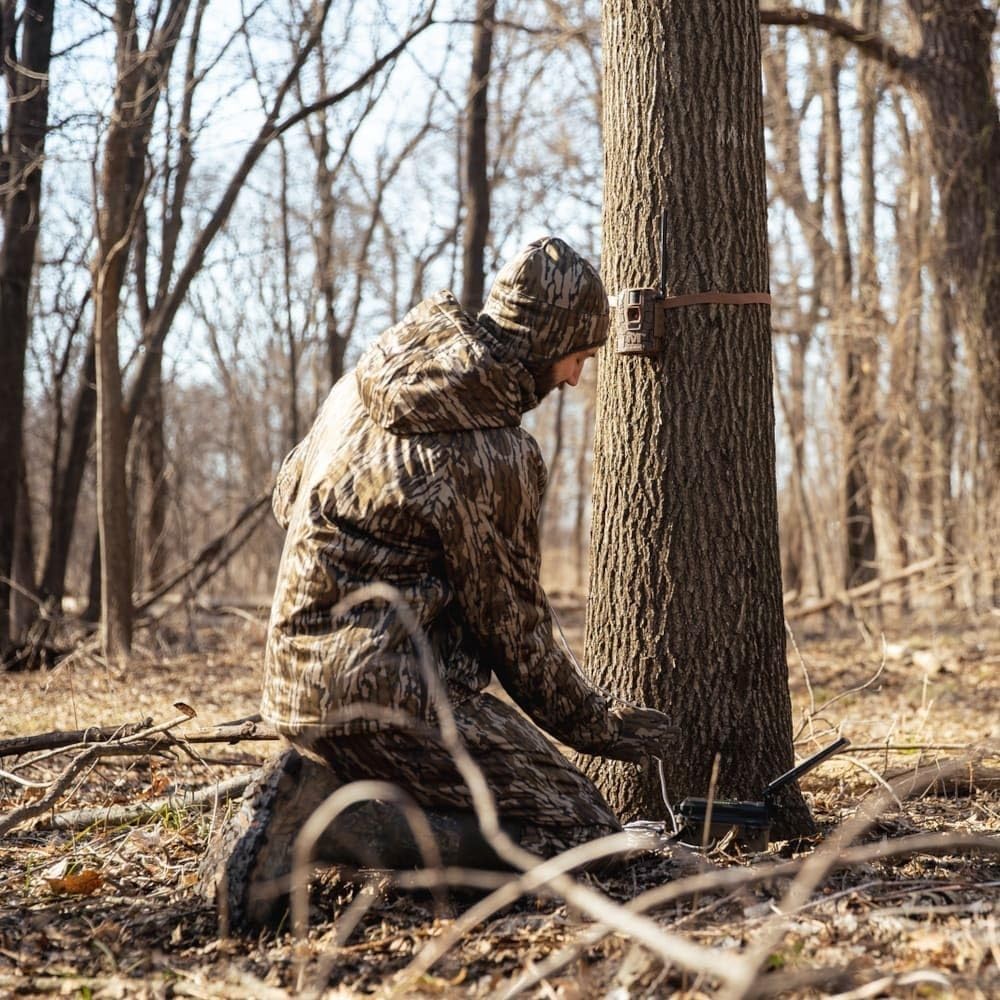 Person installing MUDDY Mitigator 2.0 camera on a tree