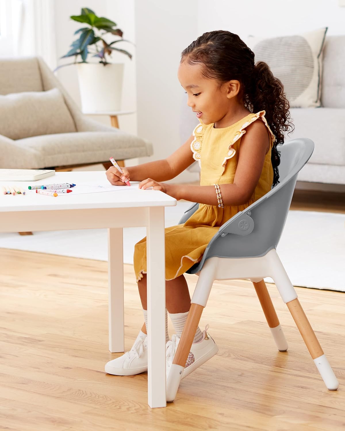 Young child sitting in the Skip Hop Eon 4-in-1 High Chair, configured as a big kid chair, at a small table.