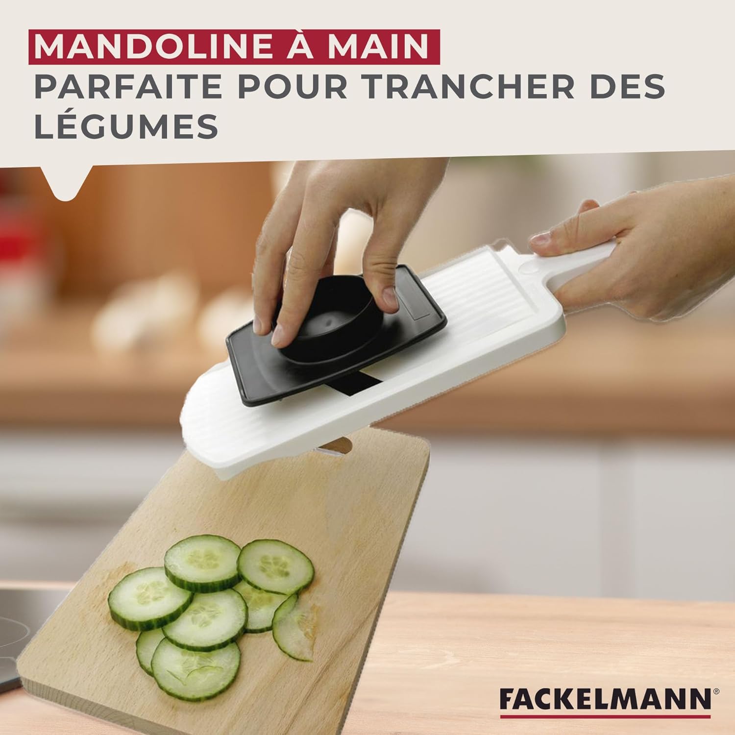 A hand using the Fackelmann mandoline slicer with the hand guard to slice a cucumber.