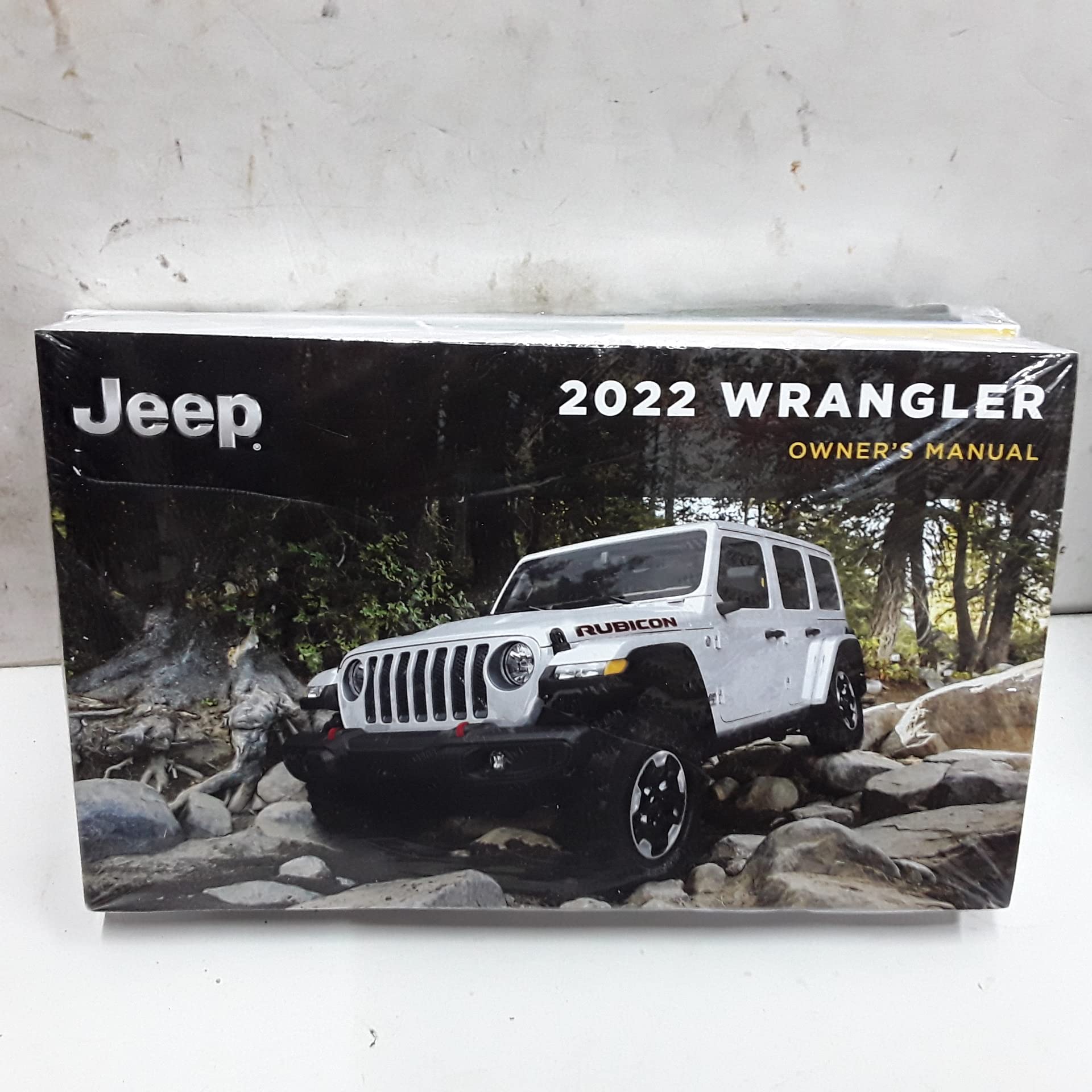 Front cover of the 2022 Jeep Wrangler Owners Manual, showing a white Jeep Wrangler Rubicon on a rocky terrain.