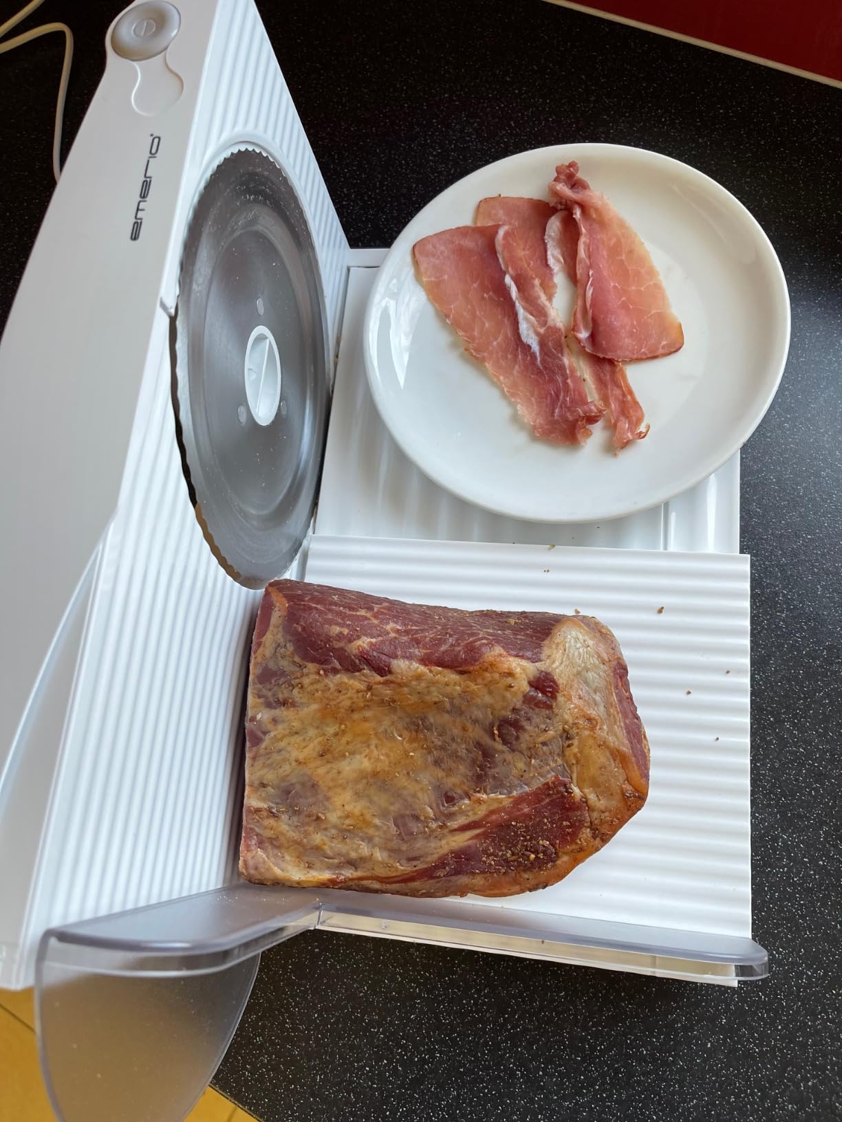 Aufgeklappter Allesschneider mit frisch geschnittenem Brot auf Holzbrett